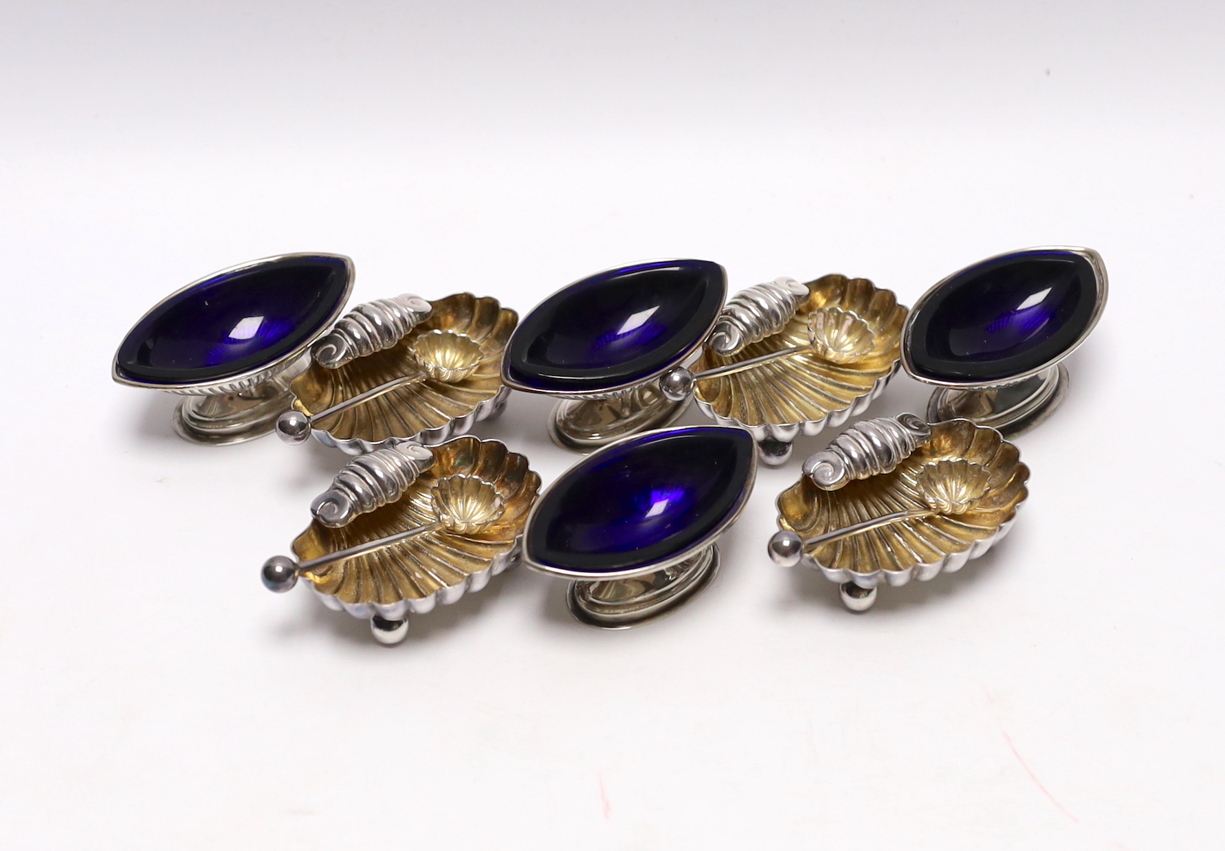 A set of four Victorian elliptical shaped silver pedestal salts, Birmingham, 1891, 58mm, with blue glass liners and a set of four silver plated salts.